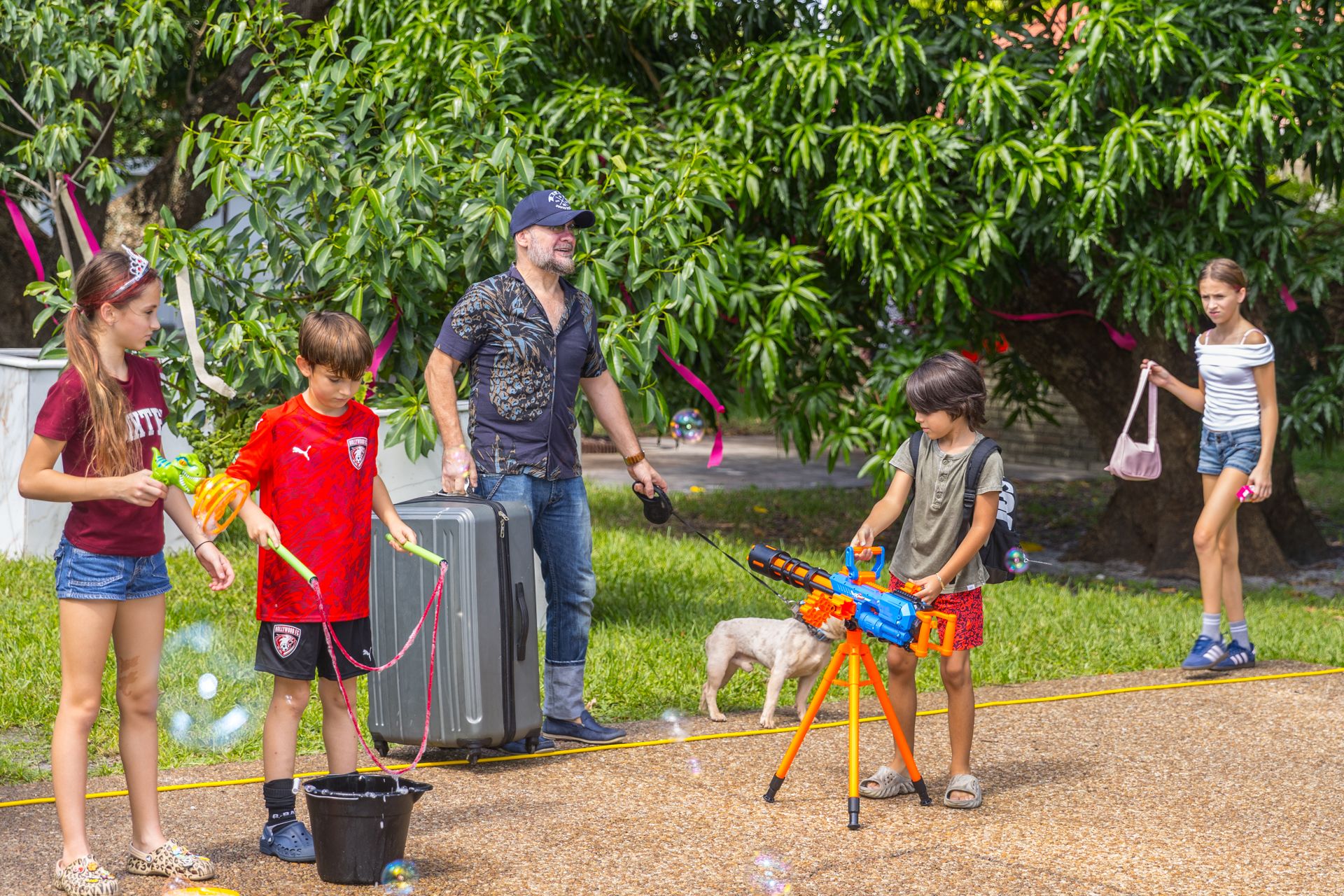 Children chase giant soap bubbles across the lawn while a parent watches